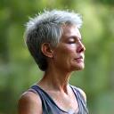 Person practicing deep breathing outdoors with a serene natural backdrop, symbolizing stress reduction.